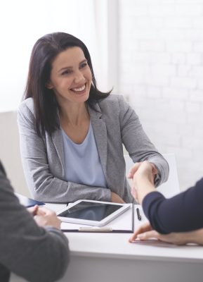 Positive insurance broker handshaking with young couple